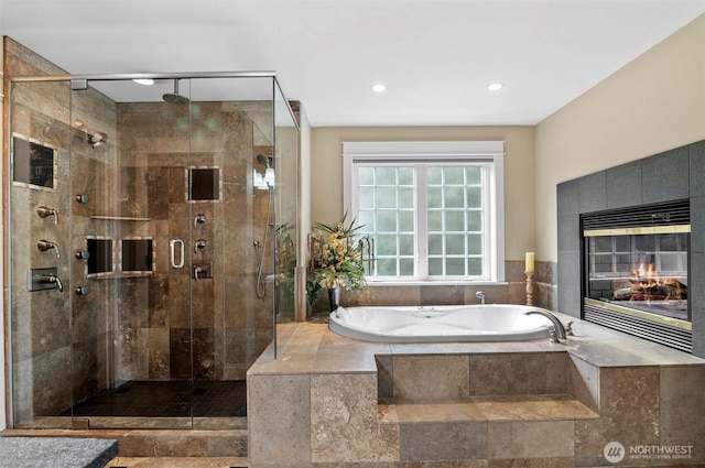 bathroom featuring a garden tub, a shower stall, and a fireplace