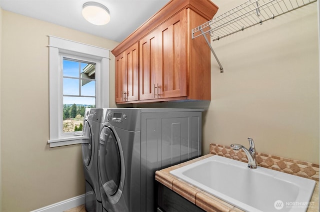 laundry room featuring a sink, washing machine and clothes dryer, cabinet space, and baseboards