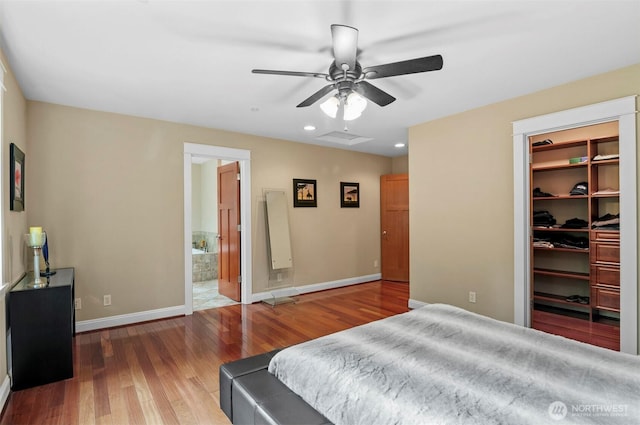 bedroom with wood finished floors, baseboards, a closet, a walk in closet, and attic access