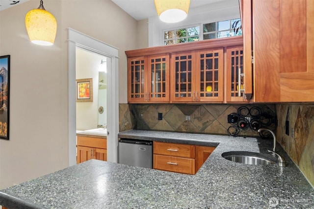 kitchen with a sink, fridge, decorative backsplash, brown cabinetry, and glass insert cabinets