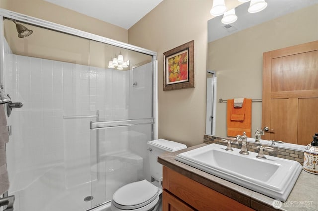 full bath with toilet, a shower stall, a notable chandelier, and vanity