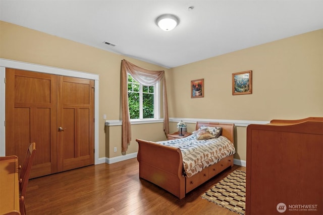 bedroom with baseboards, visible vents, and wood finished floors