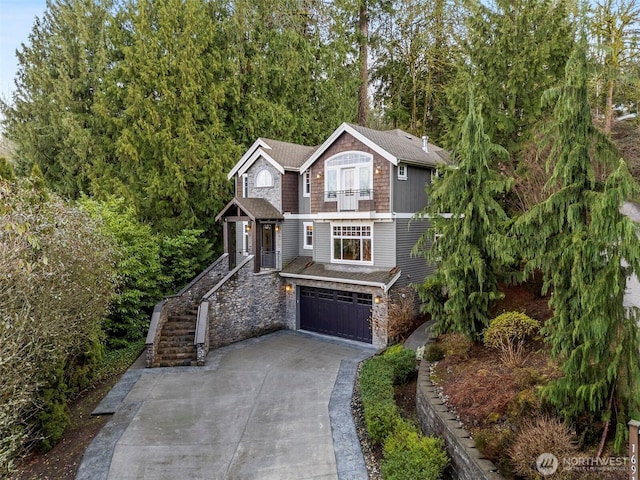 view of front facade featuring driveway, stone siding, a garage, and stairs