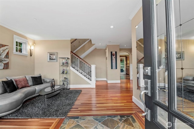 living area featuring stairway, wood finished floors, and crown molding