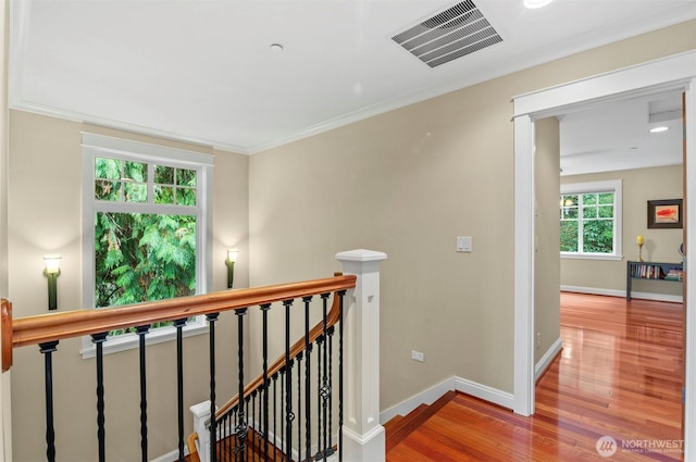 corridor featuring visible vents, wood finished floors, an upstairs landing, and baseboards