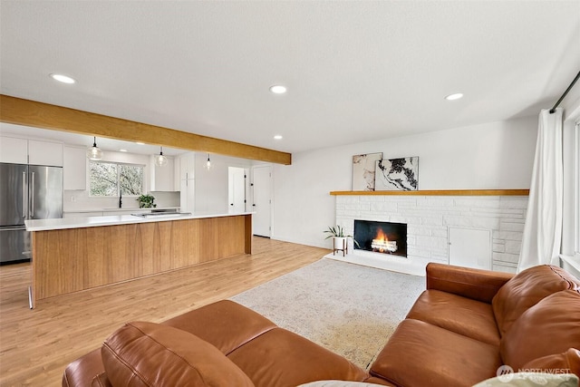 living area with light wood-style floors, a fireplace, and recessed lighting