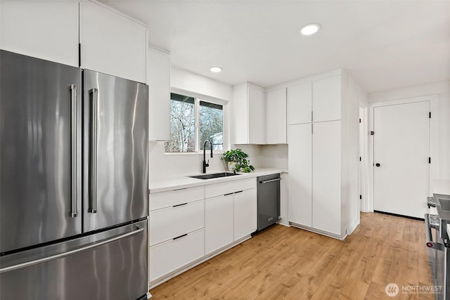 kitchen featuring stainless steel appliances, a sink, light countertops, and white cabinets