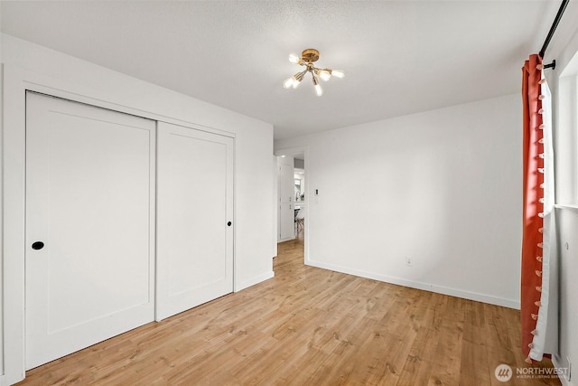 unfurnished bedroom featuring a closet, baseboards, and light wood finished floors