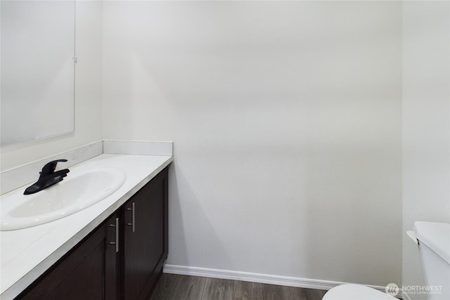 bathroom featuring toilet, wood finished floors, vanity, and baseboards