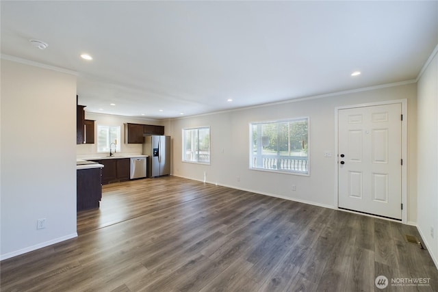 unfurnished living room with recessed lighting, dark wood-style flooring, a sink, baseboards, and ornamental molding