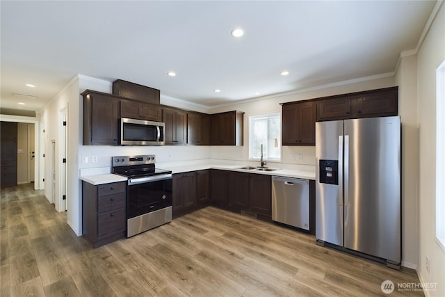 kitchen featuring appliances with stainless steel finishes, light countertops, light wood-style floors, and dark brown cabinets