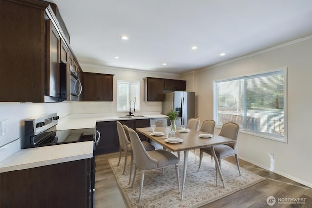 dining space featuring crown molding, baseboards, wood finished floors, and recessed lighting