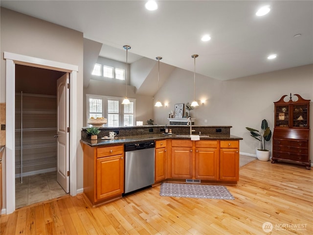 kitchen with light wood-style flooring, a sink, dishwasher, brown cabinetry, and decorative light fixtures