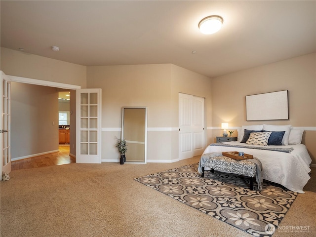 carpeted bedroom featuring a closet, french doors, and baseboards