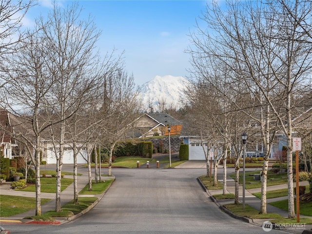 view of road with sidewalks, street lights, a mountain view, and curbs