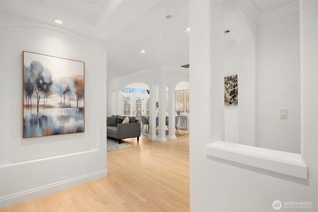 hallway featuring ornamental molding, wood finished floors, recessed lighting, baseboards, and ornate columns