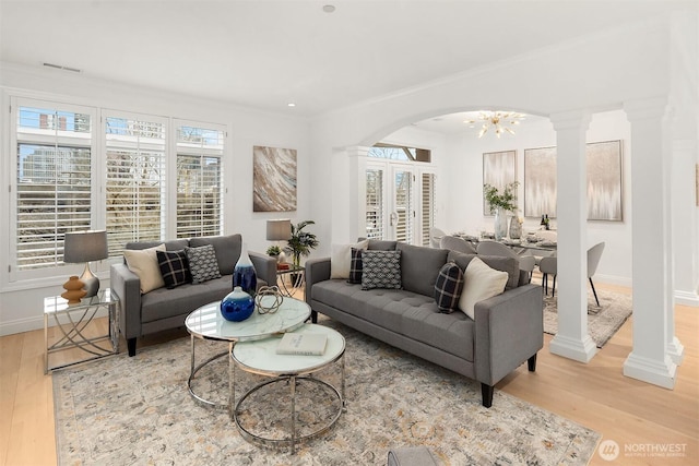 living area featuring decorative columns, wood finished floors, and visible vents