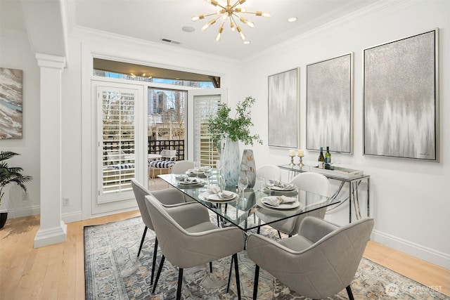 dining space featuring light wood-type flooring, visible vents, a notable chandelier, ornamental molding, and decorative columns