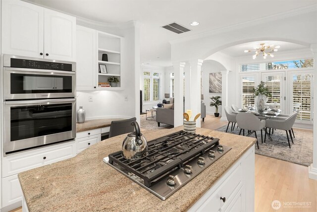 kitchen with visible vents, light stone countertops, ornamental molding, appliances with stainless steel finishes, and ornate columns