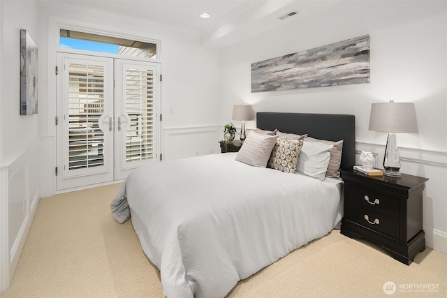 carpeted bedroom featuring visible vents, recessed lighting, wainscoting, a decorative wall, and access to outside