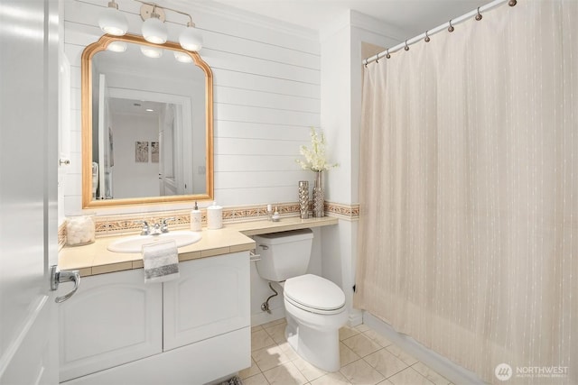 bathroom featuring wooden walls, toilet, a shower with curtain, tile patterned floors, and vanity