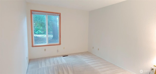 empty room featuring visible vents and light colored carpet