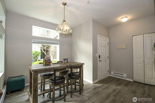 dining room with a baseboard heating unit, dark wood-style flooring, baseboards, and baseboard heating