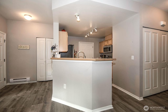 kitchen featuring baseboard heating, baseboards, stainless steel appliances, and dark wood-type flooring