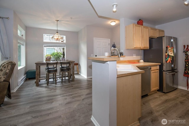 kitchen with dark wood-style flooring, light brown cabinetry, appliances with stainless steel finishes, a baseboard heating unit, and a peninsula