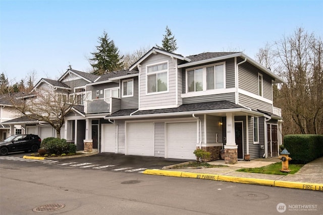 view of front of house featuring roof with shingles, an attached garage, and a balcony