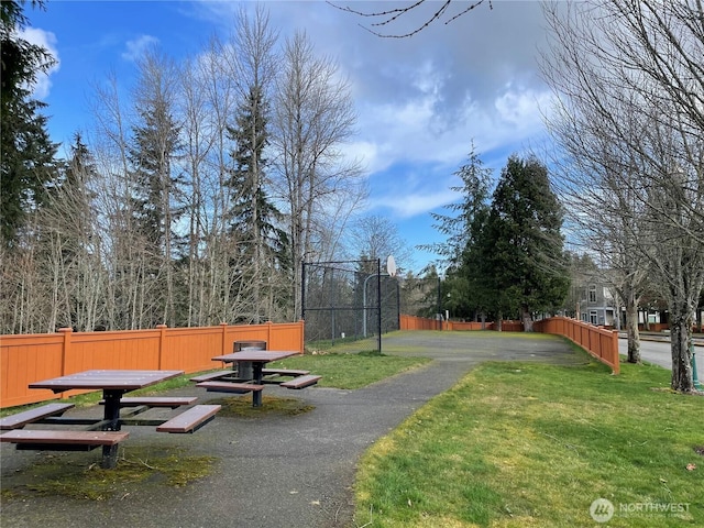 view of home's community featuring community basketball court, fence, and a lawn