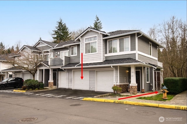 view of front of home with driveway, roof with shingles, an attached garage, and a balcony