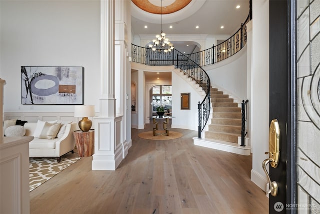 foyer featuring a tray ceiling, a notable chandelier, stairway, and hardwood / wood-style flooring