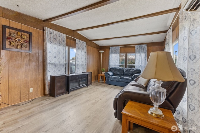 living area featuring wooden walls, beamed ceiling, a textured ceiling, and light wood-style floors