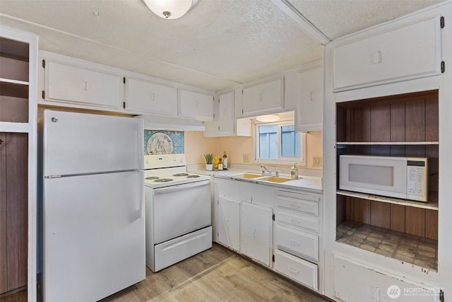 kitchen featuring white appliances, light wood-style flooring, a sink, light countertops, and white cabinetry