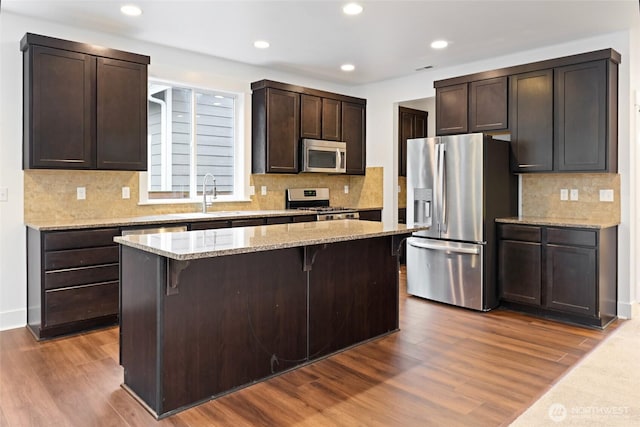 kitchen featuring appliances with stainless steel finishes, dark wood finished floors, a sink, and a breakfast bar area