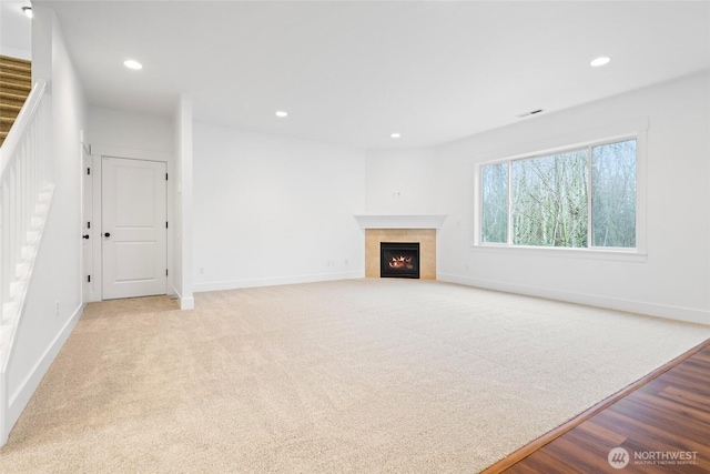 unfurnished living room with visible vents, baseboards, a tiled fireplace, carpet floors, and recessed lighting