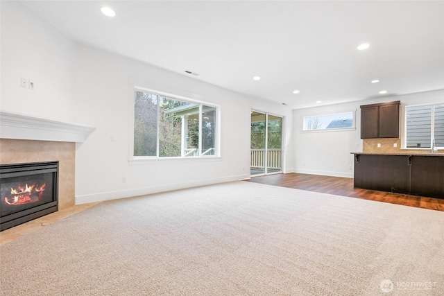 unfurnished living room with visible vents, baseboards, carpet, a fireplace, and recessed lighting