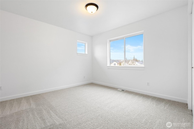 carpeted spare room featuring visible vents and baseboards