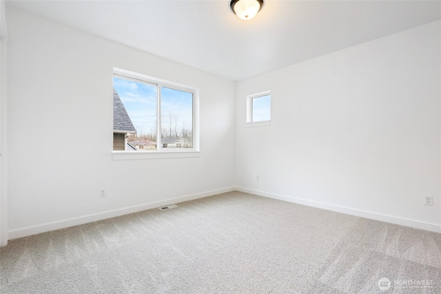 empty room featuring carpet, visible vents, and baseboards