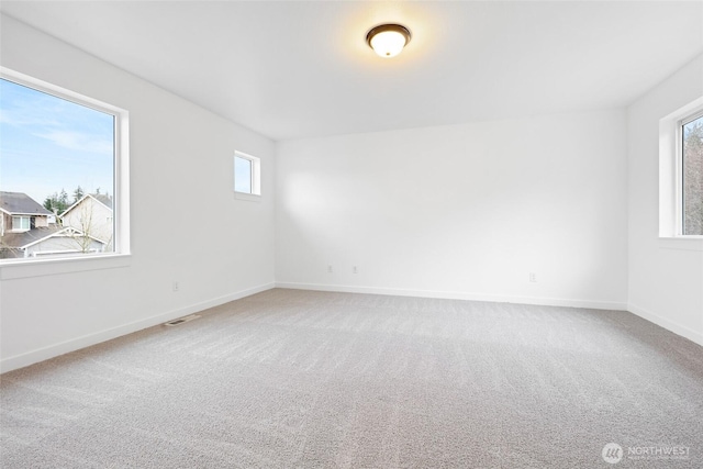 empty room featuring carpet, visible vents, and baseboards