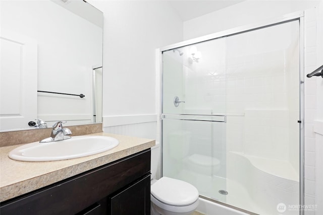 bathroom with toilet, a stall shower, and vanity