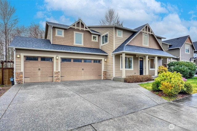 view of front facade featuring stone siding, a shingled roof, fence, and concrete driveway