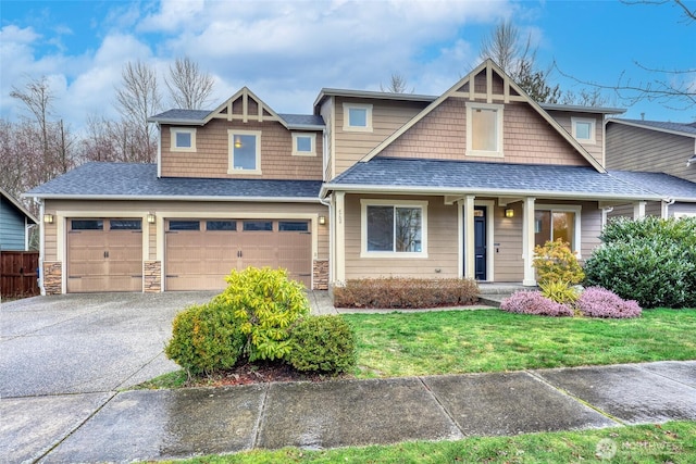 view of front facade with driveway, a shingled roof, a front lawn, and stone siding