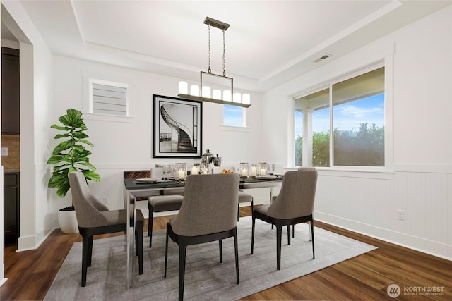 dining room featuring dark wood-style floors, a tray ceiling, and visible vents