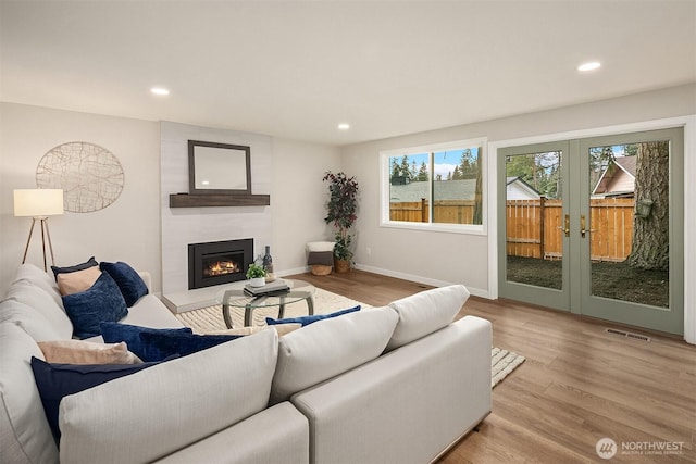 living room with baseboards, visible vents, wood finished floors, a fireplace, and recessed lighting