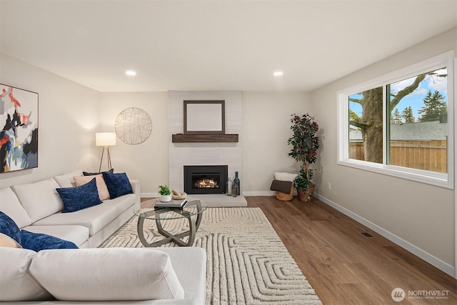 living room with recessed lighting, a fireplace, wood finished floors, and baseboards