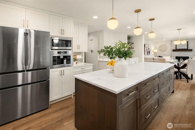 kitchen featuring white cabinets, appliances with stainless steel finishes, wood finished floors, hanging light fixtures, and recessed lighting