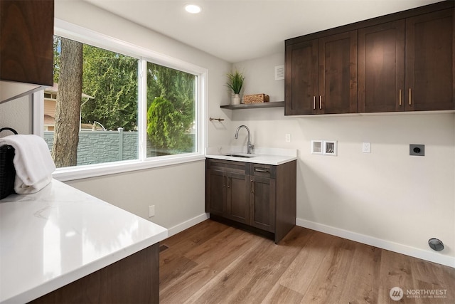 laundry room with washer hookup, cabinet space, a sink, electric dryer hookup, and light wood-type flooring