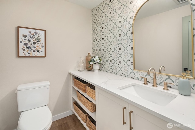 bathroom with baseboards, vanity, toilet, and wood finished floors